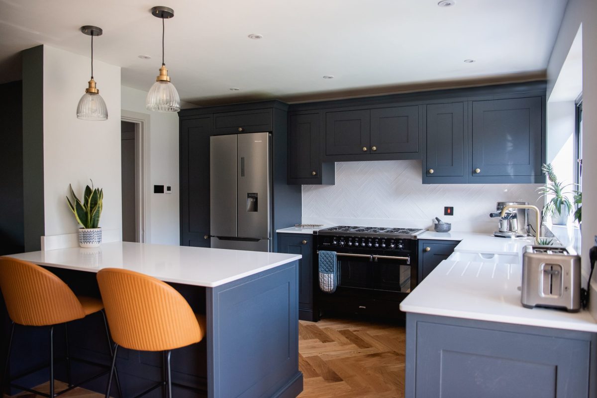 Black shaker kitchen with brass knobs and Silestone worktop, range and parquet floor
